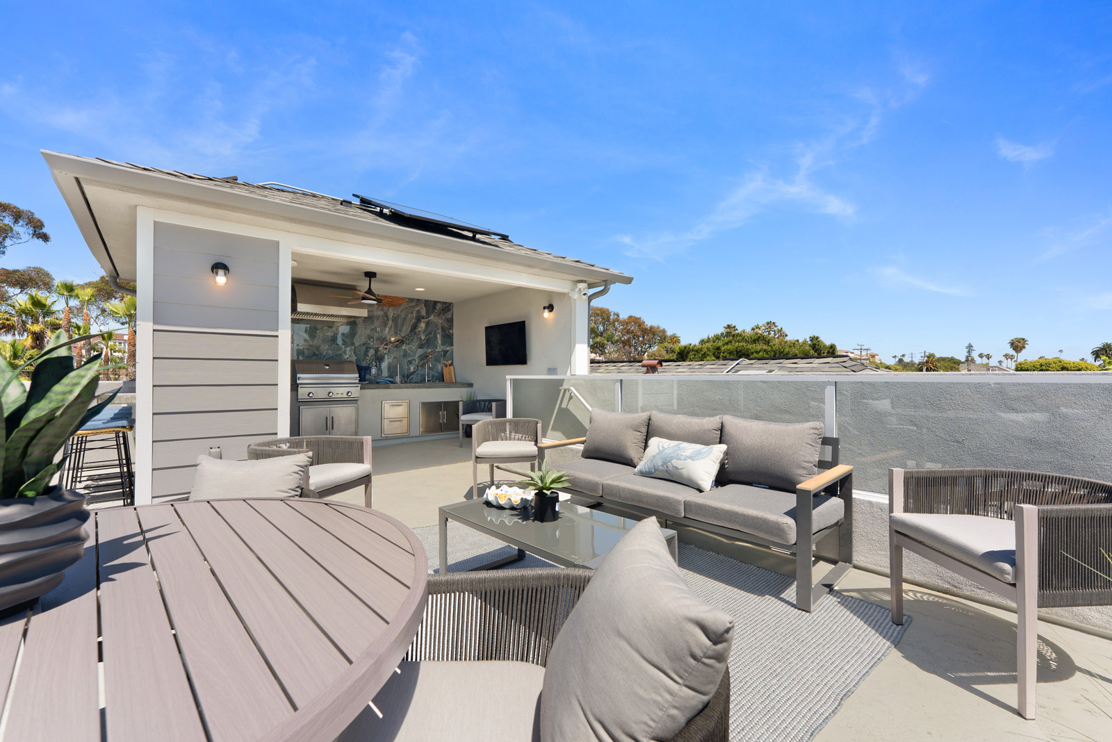 Contemporary rooftop patio with comfortable outdoor seating, dining furniture, and expansive views in a luxury multifamily development.