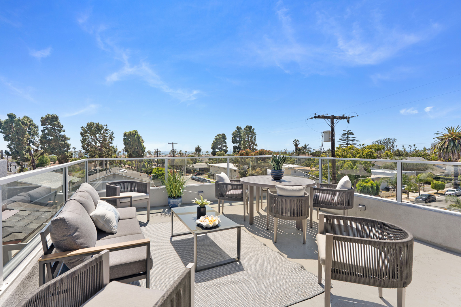 Rooftop patio featuring luxury outdoor furniture and distant ocean views from a modern Oceanside multifamily residence.